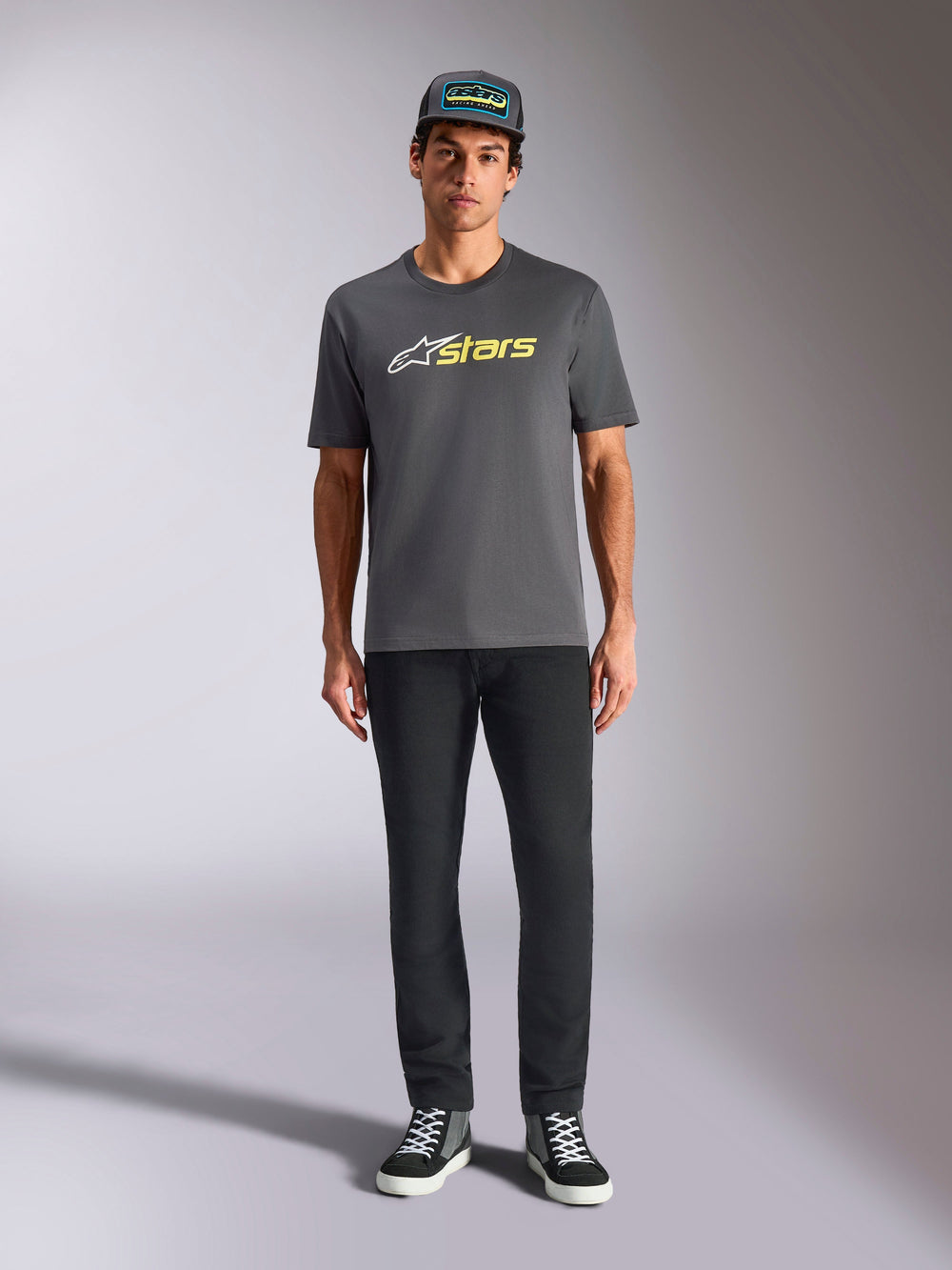 Alpinestars Blaze 2.0 CSF Tee, Short Sleeve T-Shirt, Charcoal Gray with White and Hi-Vis Yellow logo, worn with black pants and a matching trucker hat, casual motorsport lifestyle