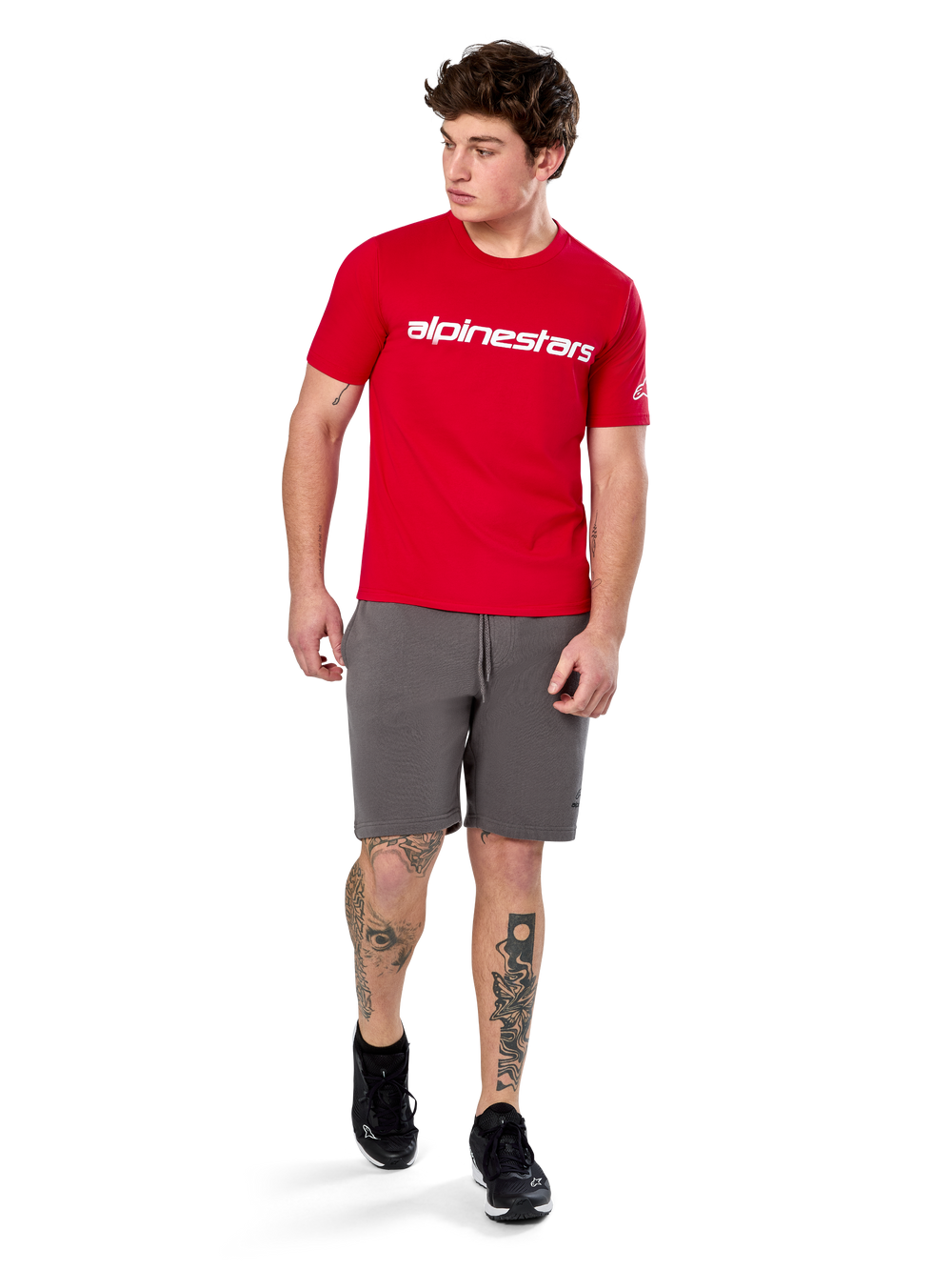 Alpinestars Linear Wordmark 2.0 CSF Tee, Short Sleeve T-Shirt, Red with white wordmark logo on chest, worn by model with grey shorts and black sneakers, casual motorsport-inspired streetwear