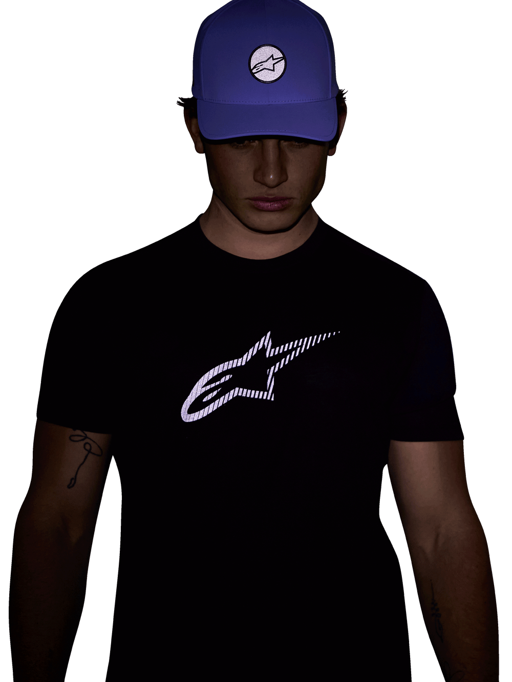 Alpinestars Exemption Performance Tee, Short Sleeve T-Shirt, Black, Featuring a large white reflective Alpinestars logo on the chest, worn with a blue cap, designed for visibility and performance sportswear