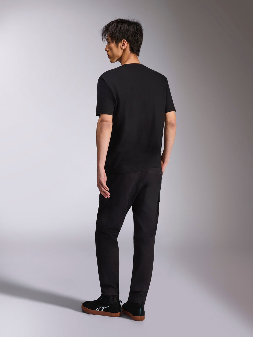 Alpinestars Noka CSF Tee, Short Sleeve T-Shirt, Black, back view shown on model, paired with black pants and casual sneakers, minimalist motorsport streetwear