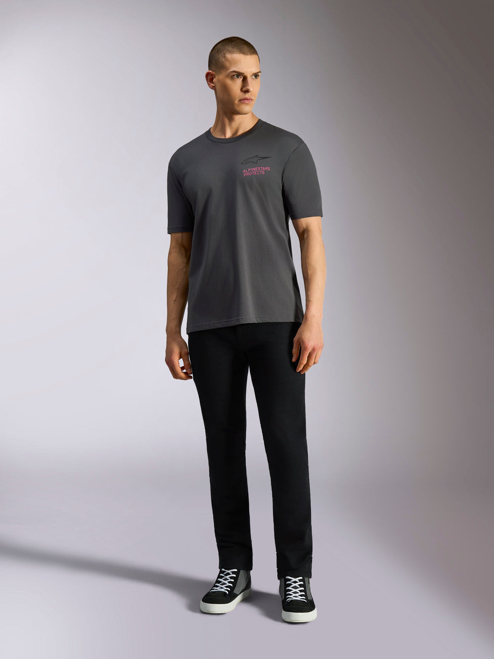 Alpinestars Pop Helmet CSF Tee, Short Sleeve T-Shirt, Charcoal Gray, featuring a pink Alpinestars logo on the chest, worn by a male model with black pants and sneakers, Casual Motorsport Streetwear