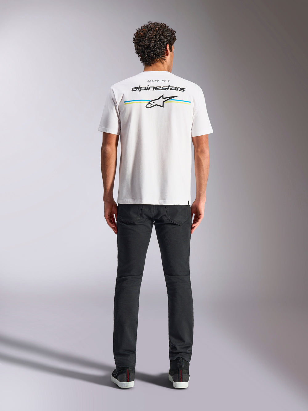Alpinestars Lanes CSF Tee, Short Sleeve T-Shirt, White, back view on model featuring Alpinestars logo and Astars star over horizontal blue and yellow stripes, casual motorsport streetwear