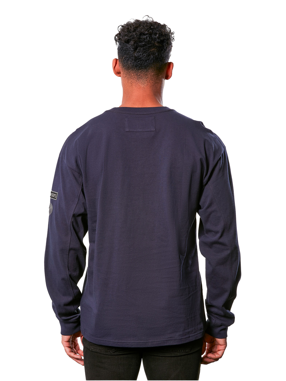 Alpinestars Vault Knit - Long Sleeve, men's long sleeve crew neck knit tee, dark navy, back view showing boxy fit, sleeve patch detailing, and heavy jersey fabric construction worn by a model