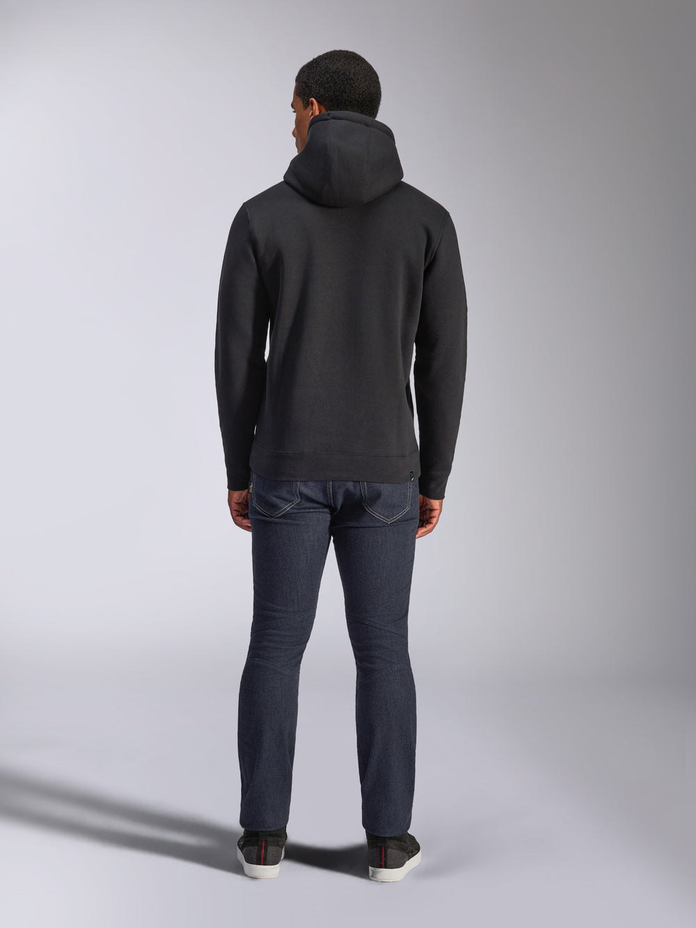 Alpinestars Blaze V3 Hoodie, casual streetwear, black, back view of hooded fleece sweatshirt, worn with dark blue denim jeans and black shoes, clean motorsport-inspired design