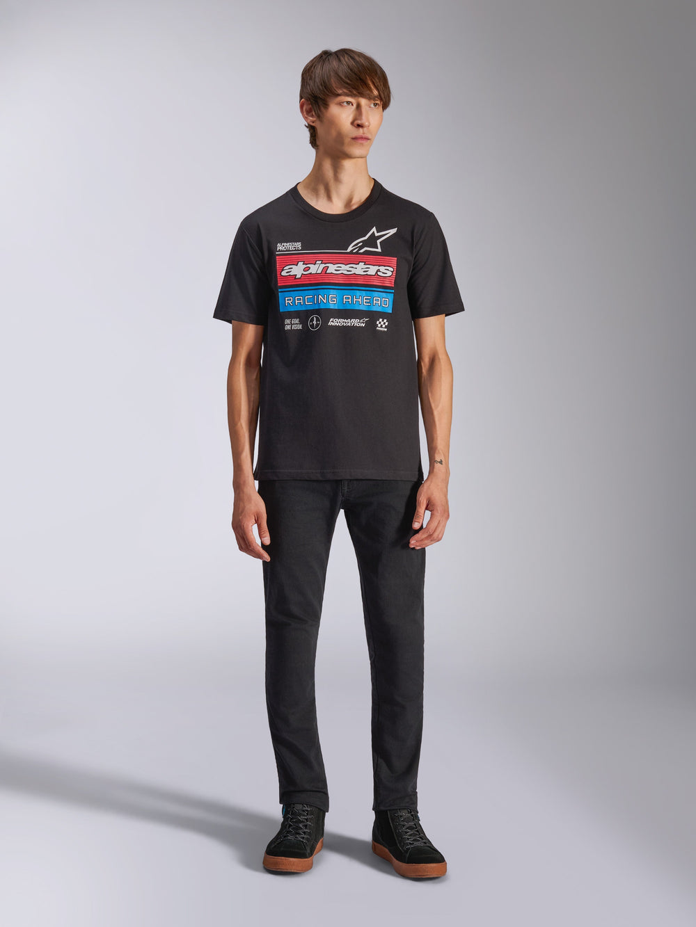 Alpinestars Harken CSF Tee, Short Sleeve T-Shirt, Black, featuring red and blue race-inspired front graphic with Alpinestars logo and 'Racing Ahead' text, worn by model with black pants, casual motorsport streetwear