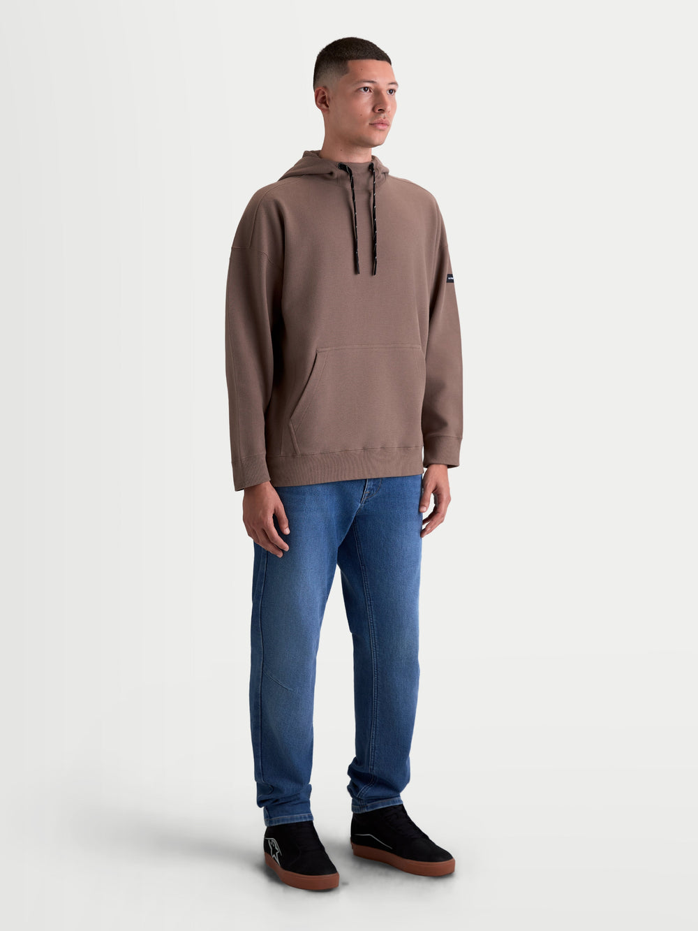 Alpinestars Camino Textured Oversized Hoodie, Men's and Women's Casual Sportswear, Brown, features textured knit twill fleece, a high collar, and a kangaroo pocket with a relaxed oversized fit, shown on model.