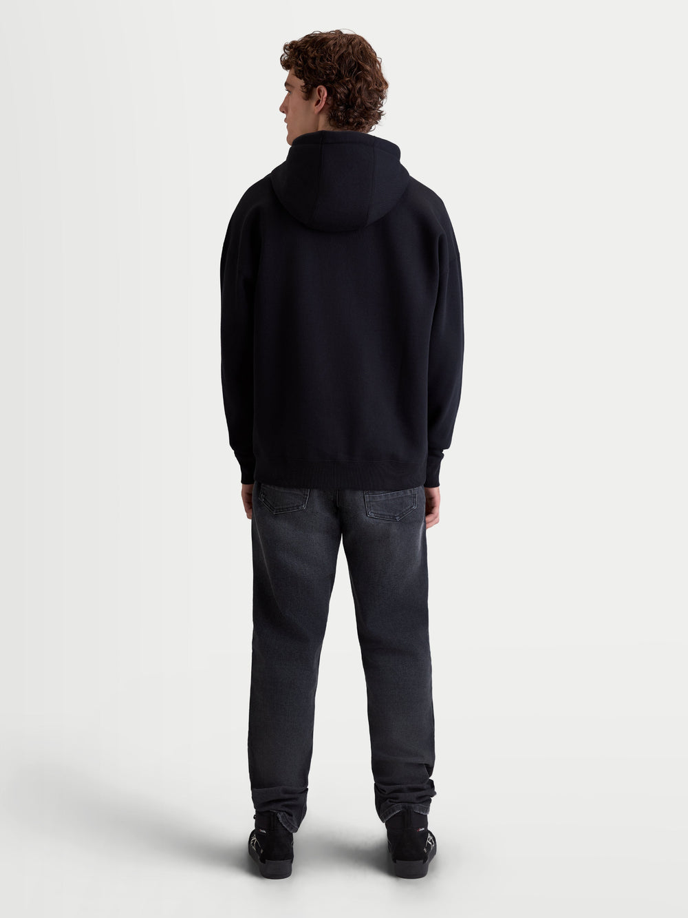 Alpinestars Prelude Oversized Hoodie, Sportswear Fleece Pullover on model, Men and Women, Black, back view highlighting the relaxed oversized silhouette and self-lined hood, casual lifestyle apparel.