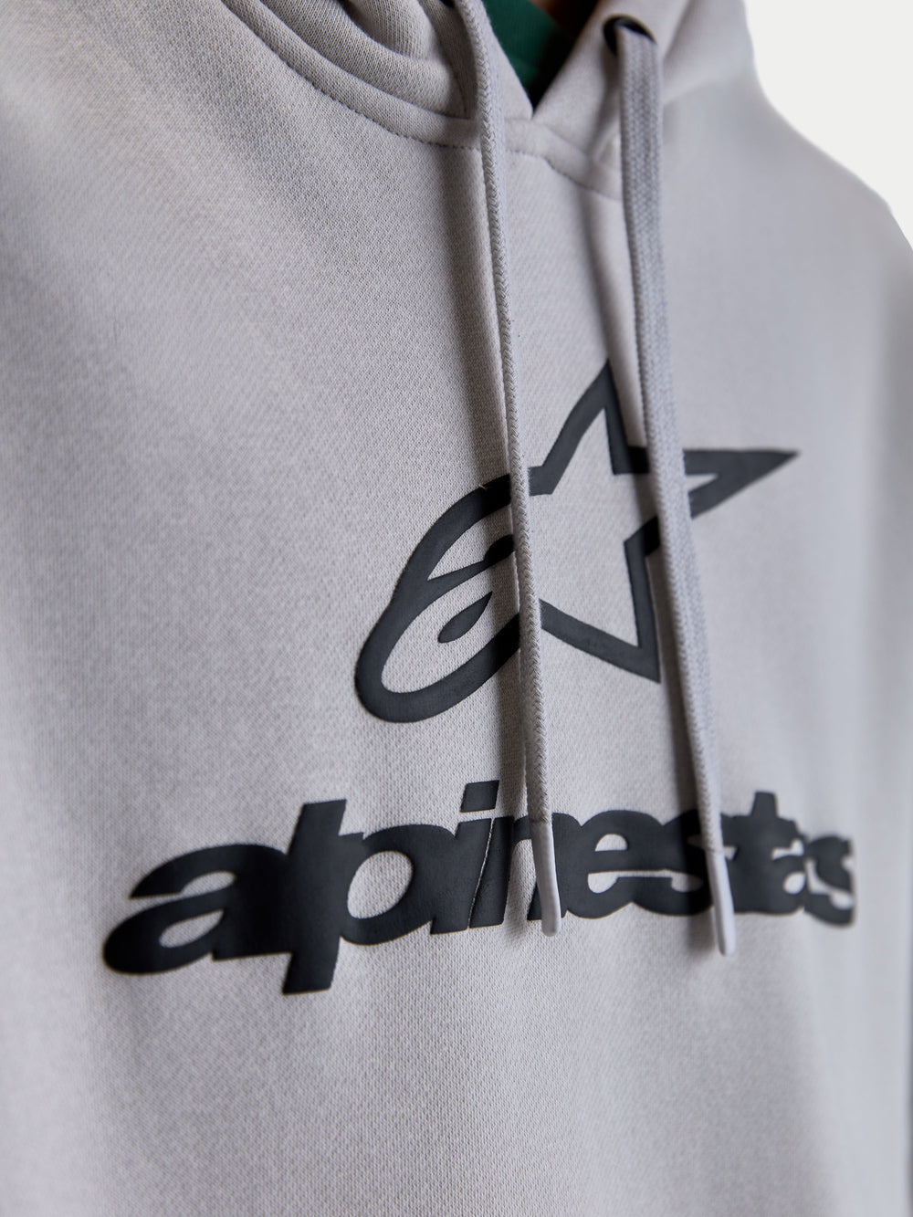 Alpinestars Prelude Oversized Hoodie, Sportswear Fleece Pullover, Unisex, Cement Gray and Black, Close-up of puff-print Alpinestars chest logo and flat hood drawcords.