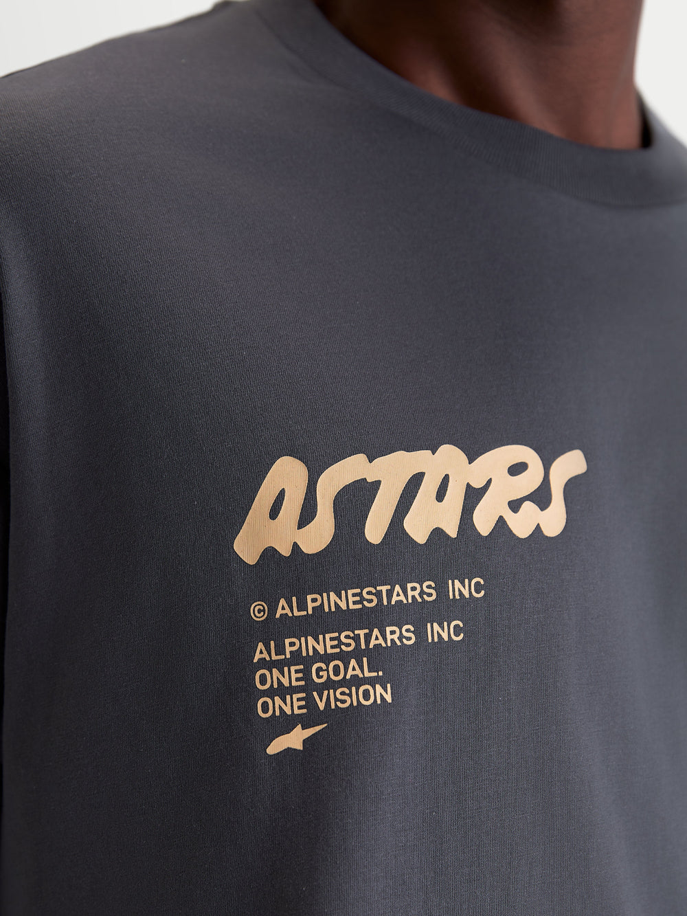 Alpinestars Chalk Oversized CSF Tee, Unisex Sportswear Short Sleeve T-Shirt, Charcoal Gray with Cream Graphic, Close-up detail of front chest logo featuring Astars branding and One Goal One Vision manifesto, premium cotton-poly blend.