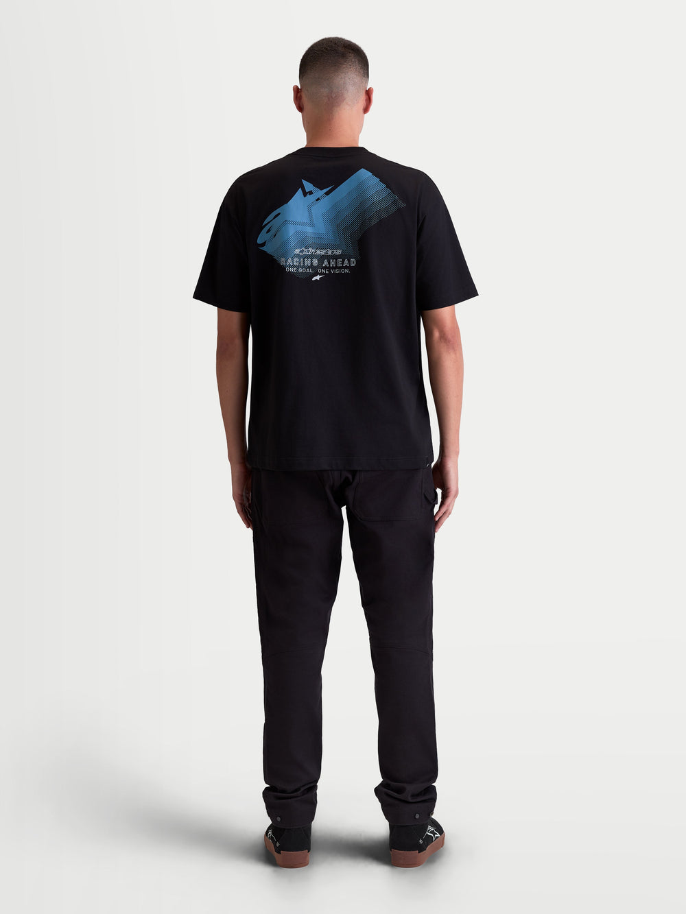 Alpinestars Ghost Oversized CSF Tee, Men's Sportswear Short Sleeve T-Shirt in Black, featuring a Blue fade logo graphic on the back with 'Racing Ahead' and 'One Goal. One Vision.' text, relaxed oversized fit, motorsport-inspired lifestyle apparel, back view on-model.