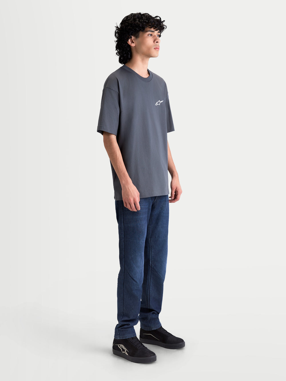 Alpinestars Mandate Oversized CSF Tee, Unisex Short Sleeve Sportswear T-Shirt, Gray Charcoal, featuring a relaxed oversized fit and puff-print Astars logo, shown on model side view.