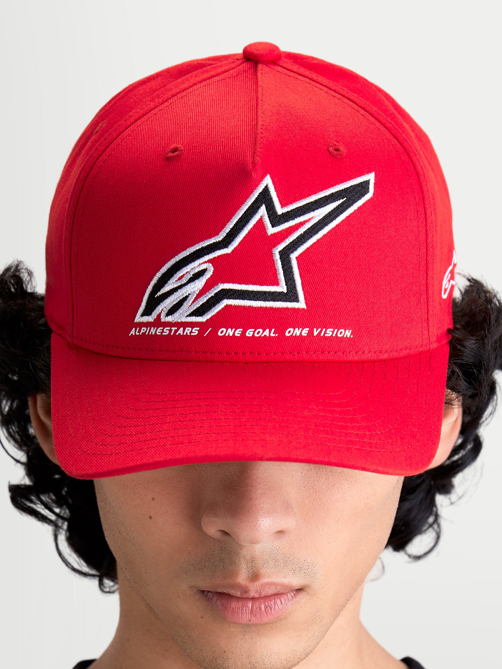 Alpinestars Lineout Hat, Red Sportswear Baseball Cap, on-model front view with a structured crown and curved bill. Features a large embroidered Astars logo in white and black with the brand motto 'ONE GOAL. ONE VISION.' underneath. Casual and performance-inspired red textile headwear for motorsports enthusiasts.