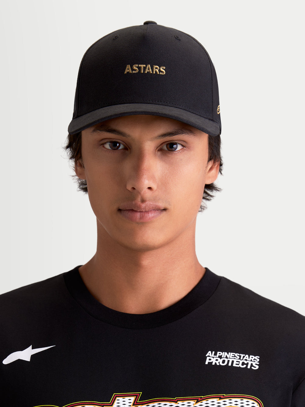 Alpinestars County Canvas Hat, Sportswear Curved Bill Baseball Cap, Black with Gold ASTARS Logo Embroidery, Oxford Peached Fabric and Structured Crown, Casual Lifestyle Wear on Model.