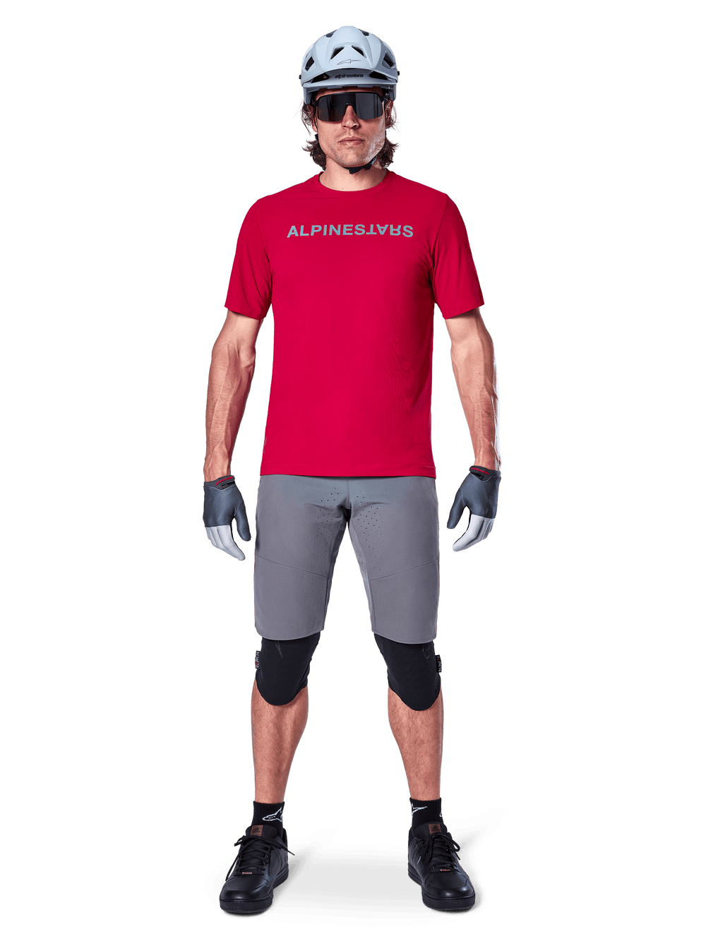 Alpinestars A-Aria Elite Shorts, Men's MTB Cycling Shorts in Dark Gray, with flexible stretch fabric and a red racing jersey.