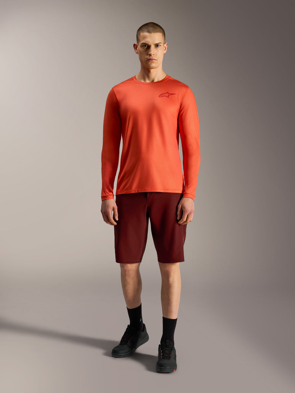 2026 Alpinestars A-Dura Ride Shorts in Bordeaux and orange long-sleeve jersey, performance mountain bike apparel for men.