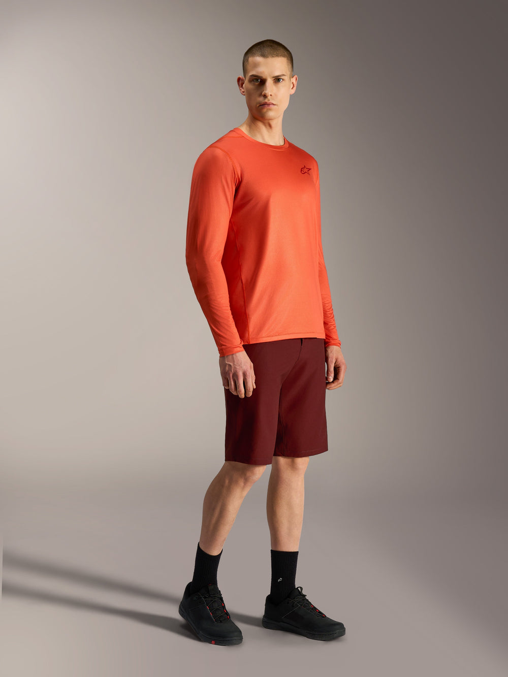 Alpinestars A-Dura Air orange long-sleeve jersey and bordeaux A-Dura Ride shorts, professional MTB performance gear.