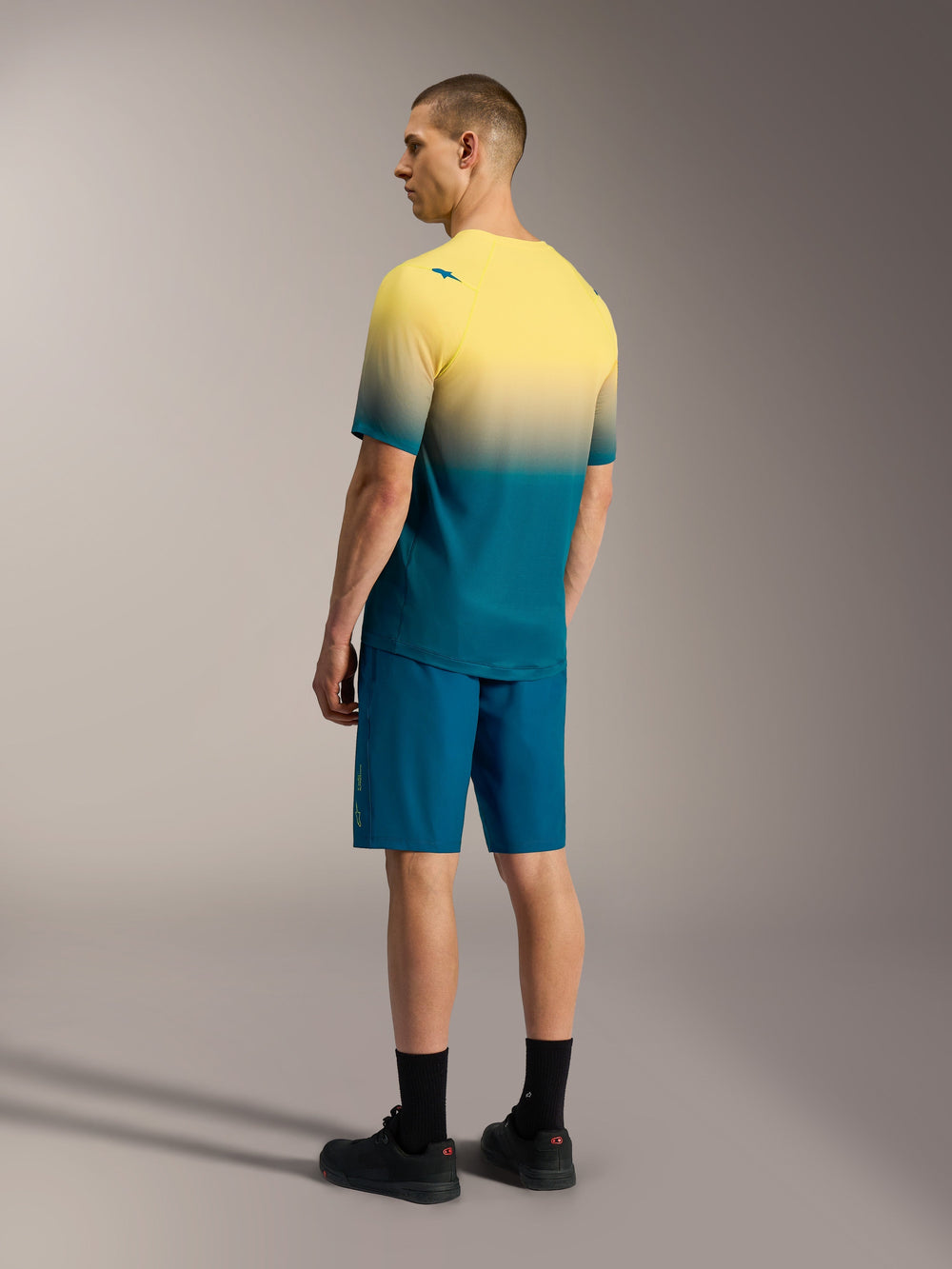 A-Dura ASTARS 2.0 Short Sleeve MTB Jersey in yellow and teal gradient, paired with matching blue performance shorts.