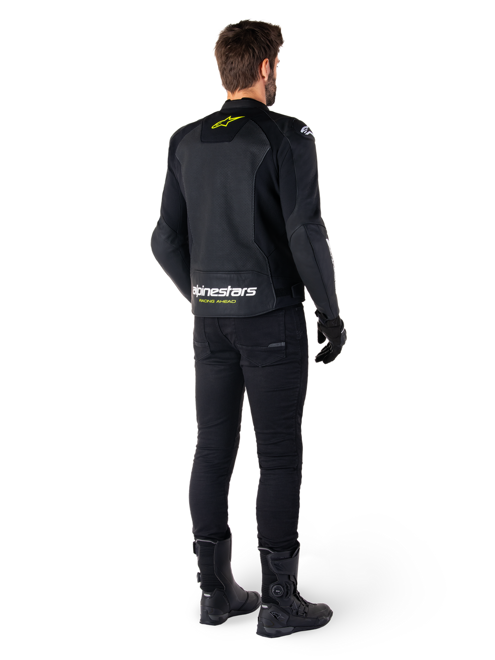 Rear view of a rider wearing the Alpinestars Faster V3 Airflow Leather Jacket, Black with White and Yellow Fluo accents, paired with black pants and boots, featuring perforated leather for ventilation and bold 'RACING AHEAD' branding on the lower back.