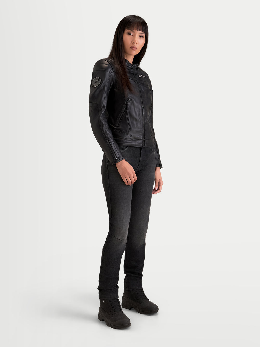 Alpinestars Revea Women Leather Jacket, women's urban contemporary motorcycle jacket in black, three-quarter view on a model wearing dark jeans and riding boots, full-grain bovine leather construction with AA safety rating