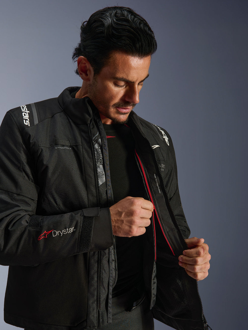 Alpinestars Andes V4 Drystar® Jacket, Black adventure motorcycle jacket, man demonstrating the internal thermal liner and red zipper, featuring Drystar® sleeve branding, durable textile material for all-weather riding
