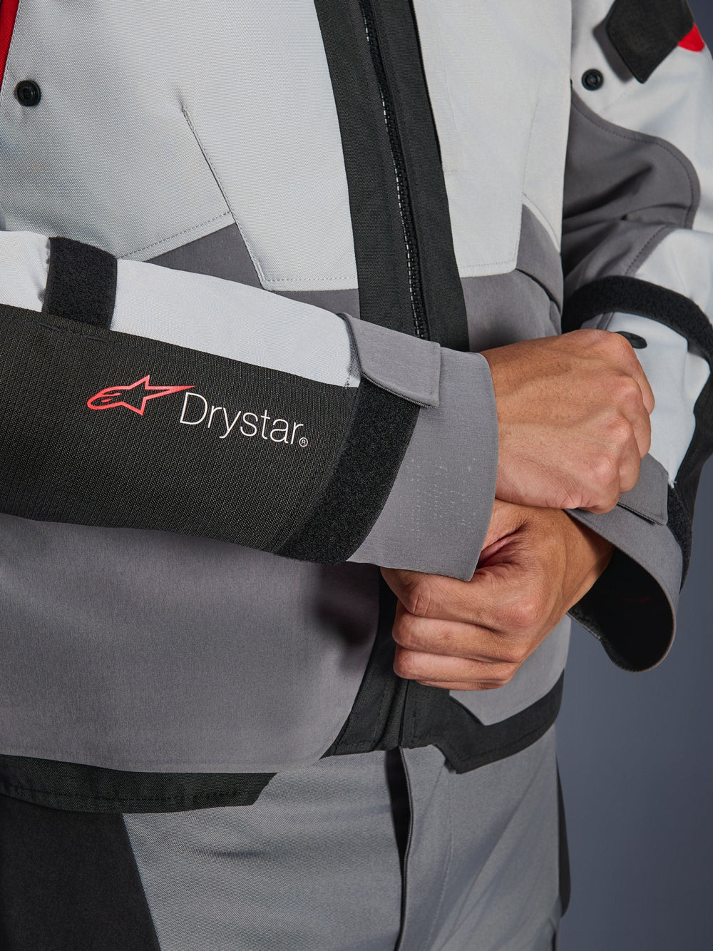 Close-up detail of Alpinestars Andes V4 Drystar® Jacket sleeve, Gray and Black textile, featuring red and white Drystar logo on forearm, adjustable velcro wrist closure, high-performance waterproof motorcycle gear