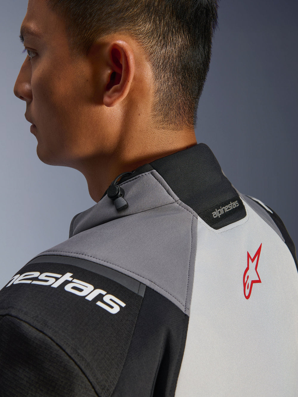 Alpinestars Andes V4 Drystar® Jacket, close-up of the collar and upper back, Dark Gray and Ice Gray with Black accents, red star logo, featuring a collar drawstring adjuster and Alpinestars branding, durable textile construction