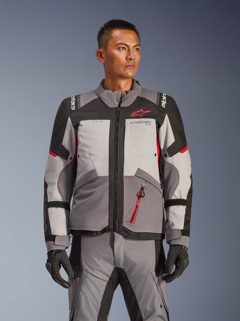 Alpinestars Andes V4 Drystar® Jacket, Motorcycle Adventure Touring Jacket, Dark Gray and Ice Gray with Black and Bright Red accents, worn with matching pants and gloves, waterproof and breathable design for all-weather adventure riding