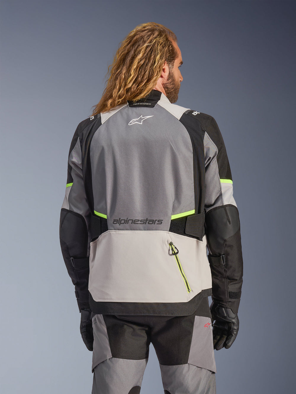 Alpinestars Andes V4 Drystar® Jacket, back view of adventure motorcycle jacket in dark gray, ice gray, and black with fluorescent yellow fluo accents, featuring reinforced textile panels and Alpinestars branding, worn with matching riding pants and black gloves