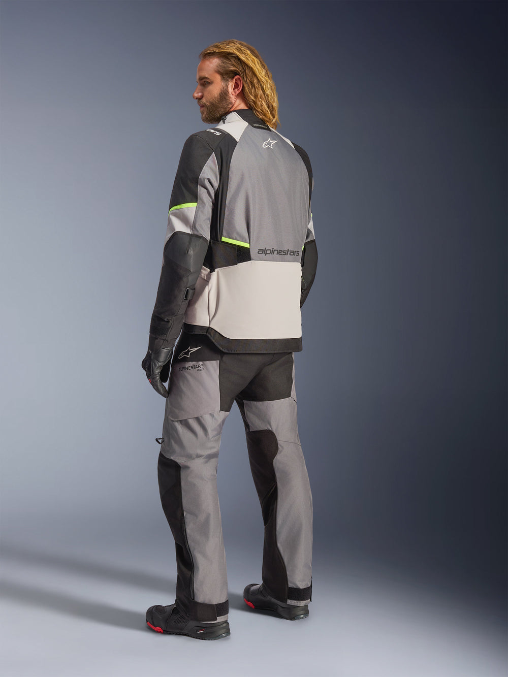 Alpinestars Andes V4 Drystar® Jacket, Dark Gray Ice Gray Black and Yellow Fluo, back view of rider wearing matching adventure touring pants and boots, featuring reinforced gray textile panels, neon yellow accents, and Alpinestars branding, all-weather motorcycle gear.
