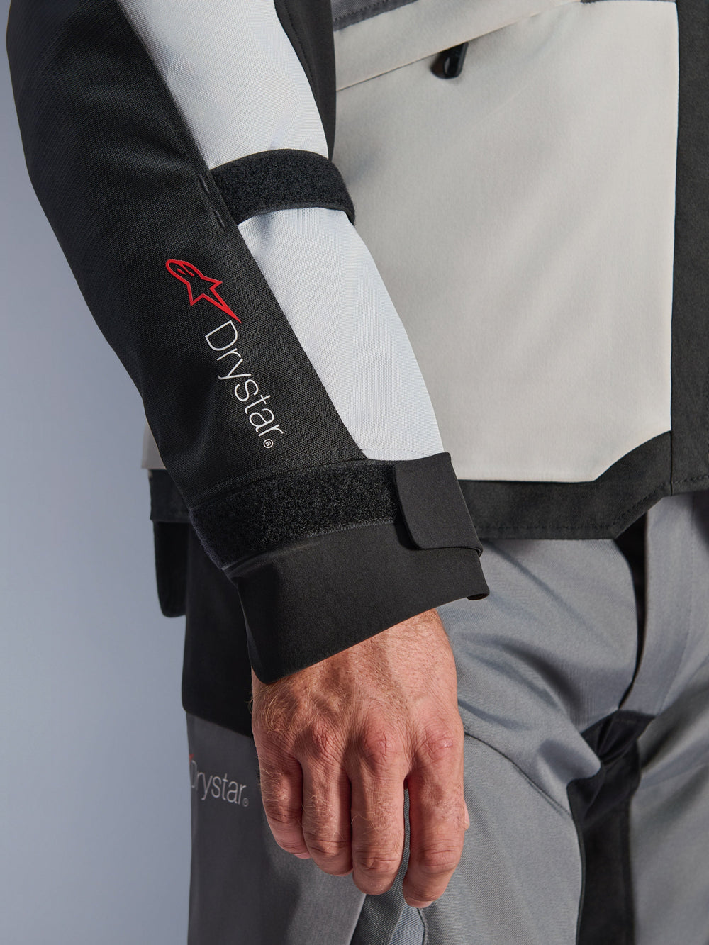 Alpinestars Andes V4 Drystar® Jacket, adventure motorcycle jacket, Ice Gray and Black panels, close-up of sleeve featuring red Drystar® logo and adjustable straps, functional textile design for all-weather riding