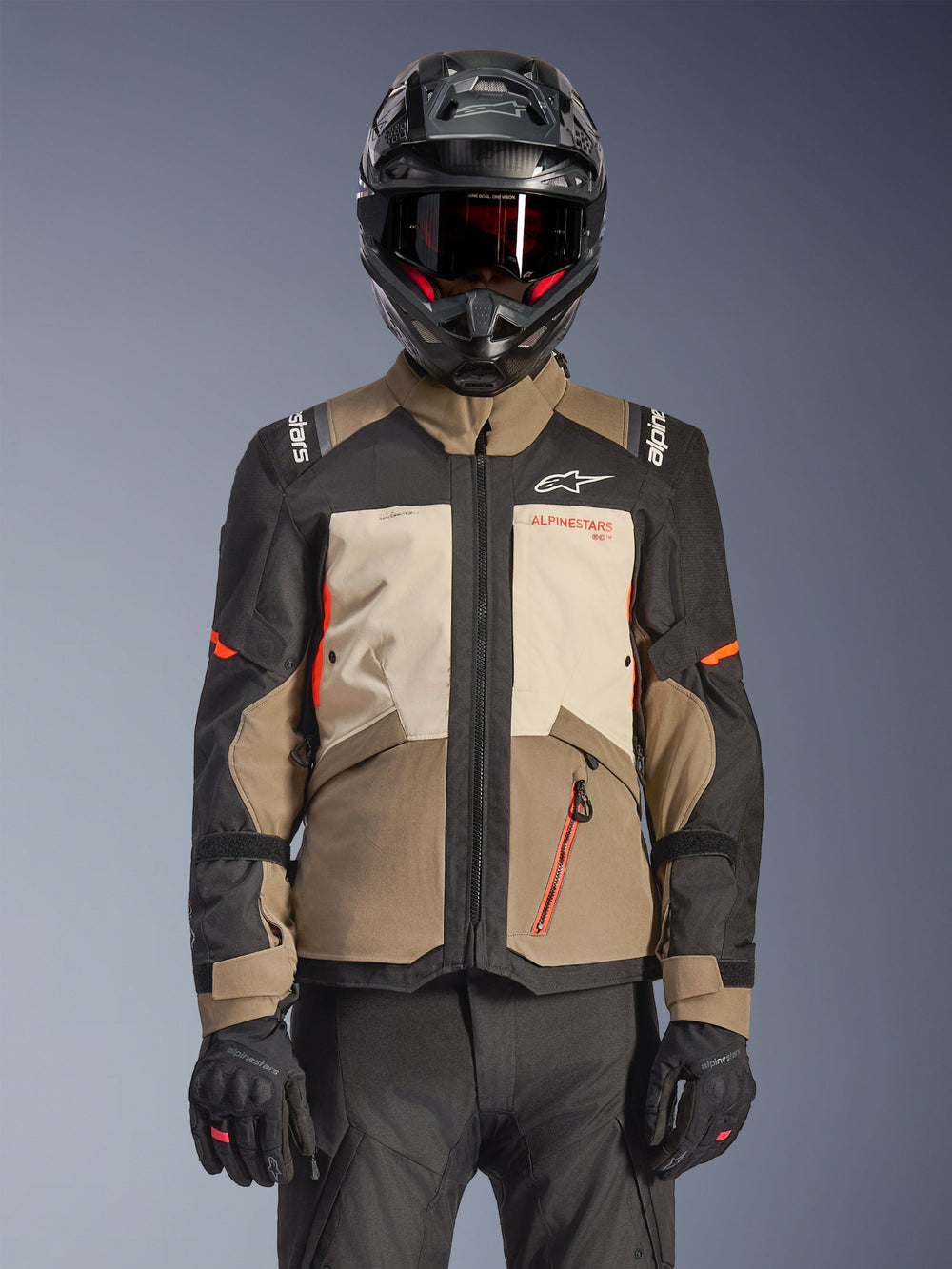 Alpinestars Andes V4 Drystar® Jacket, Walnut Mastic Black, adventure touring jacket featuring walnut brown and mastic cream panels, black sleeves, and bright orange accents, worn with a black motorcycle helmet, dark goggles, and black gloves