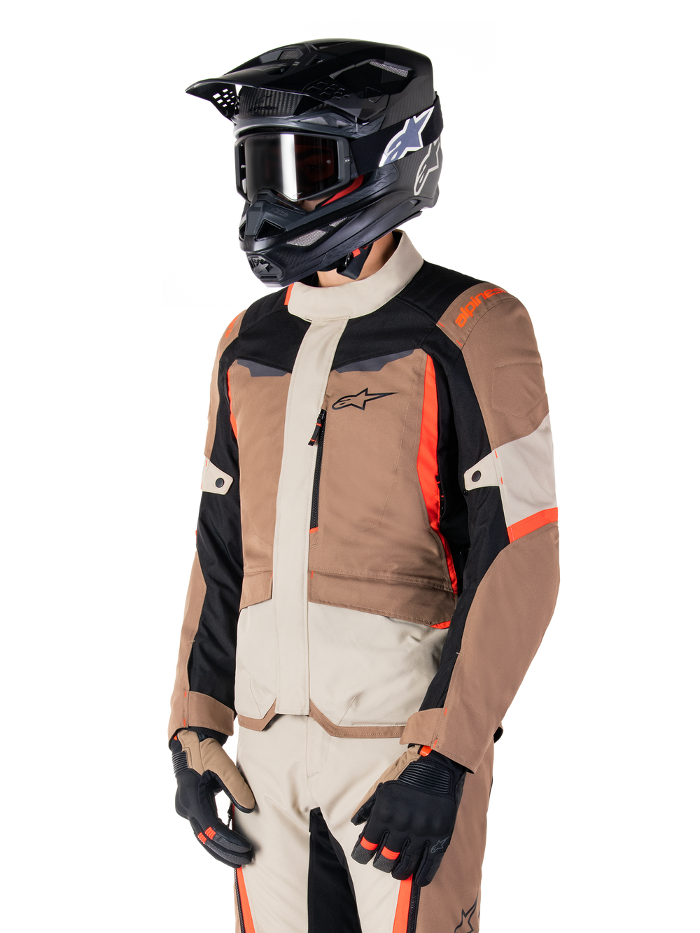 Alpinestars ST-1 Waterproof Jacket, Adventure Touring Jacket, Dark Khaki Sand Black and Red Fluo, worn by a rider with a black motocross helmet and goggles, featuring a multi-panel design with cargo pockets and Alpinestars branding on the chest