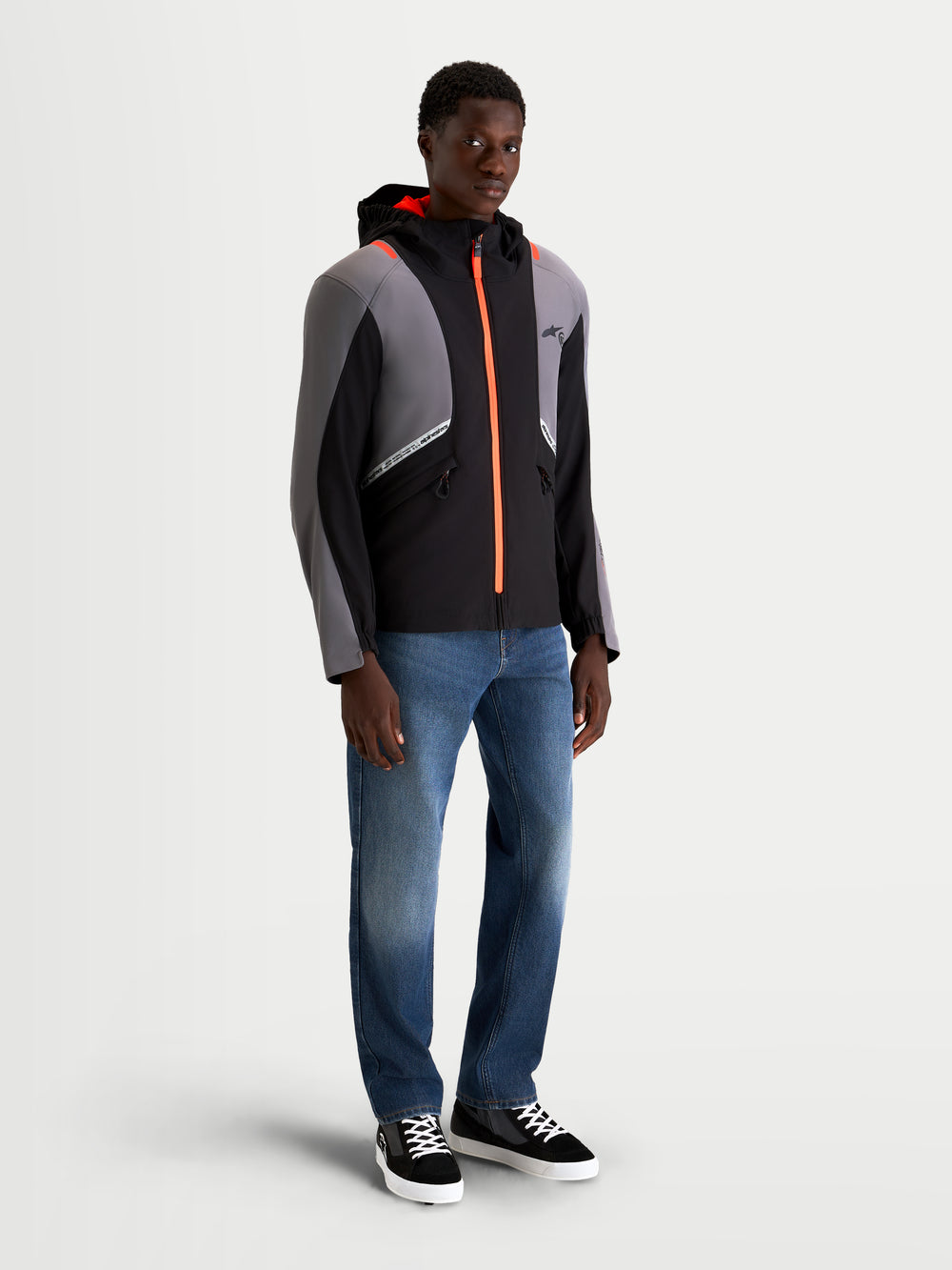 Alpinestars C-5 Drystar Jacket, men's urban contemporary motorcycle textile jacket in black and dark gray, featuring an integrated hood, waterproof construction, and bright orange zipper details worn by a model.