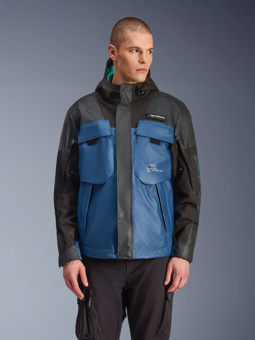 Alpinestars Mospher Waterproof Jacket, Urban Motorcycle Parka, Black and Dark Petrol Blue, featuring large tactical chest pockets, high collar with hood, technical ripstop texture, front view on model