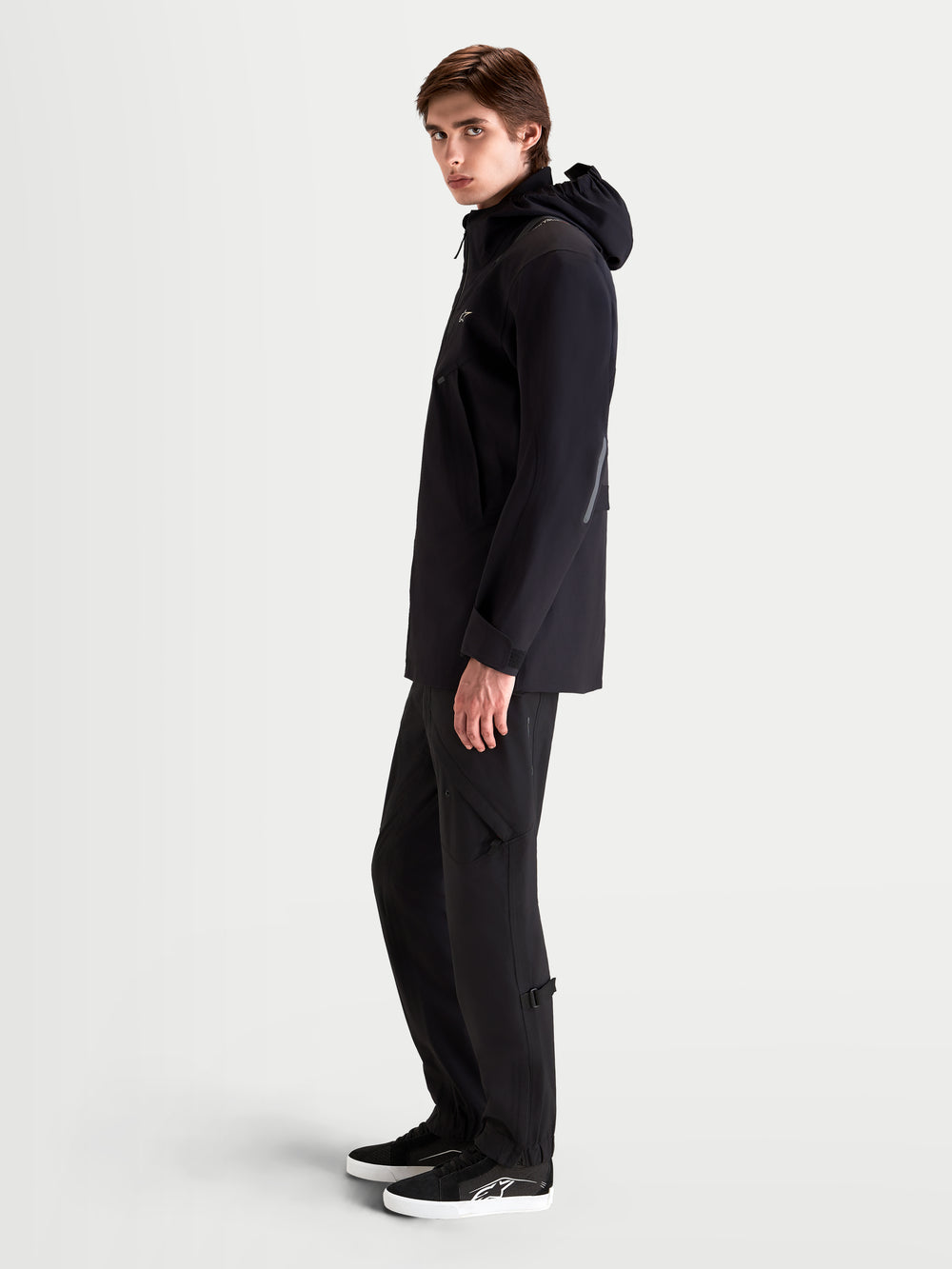 Alpinestars C-7 Drystar®XF Jacket, men's urban contemporary motorcycle jacket in black, side profile view on a model wearing matching textile riding apparel and an integrated hood.