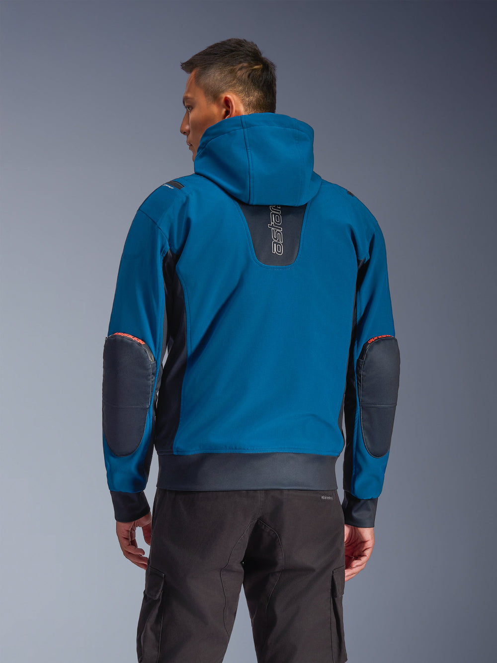 Alpinestars Moblast Waterproof Jacket, Dark Petrol and Dark Navy, urban motorcycle hoodie seen from the back, featuring a fixed hood, vertical 'astars' logo on the upper back, dark reinforced elbow patches, elasticated waist and cuffs, modern technical riding apparel
