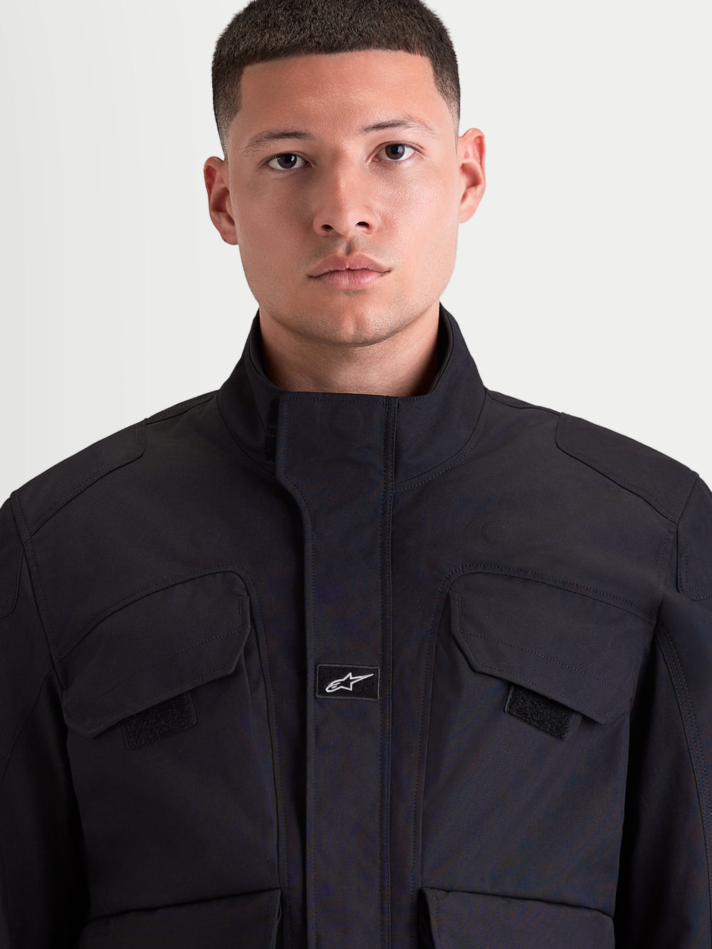 Alpinestars Altan Drystar Jacket, men's urban contemporary motorcycle jacket in black, front close-up view showing matte polyfabric construction, integrated warm collar, and chest cargo pockets worn by a model.