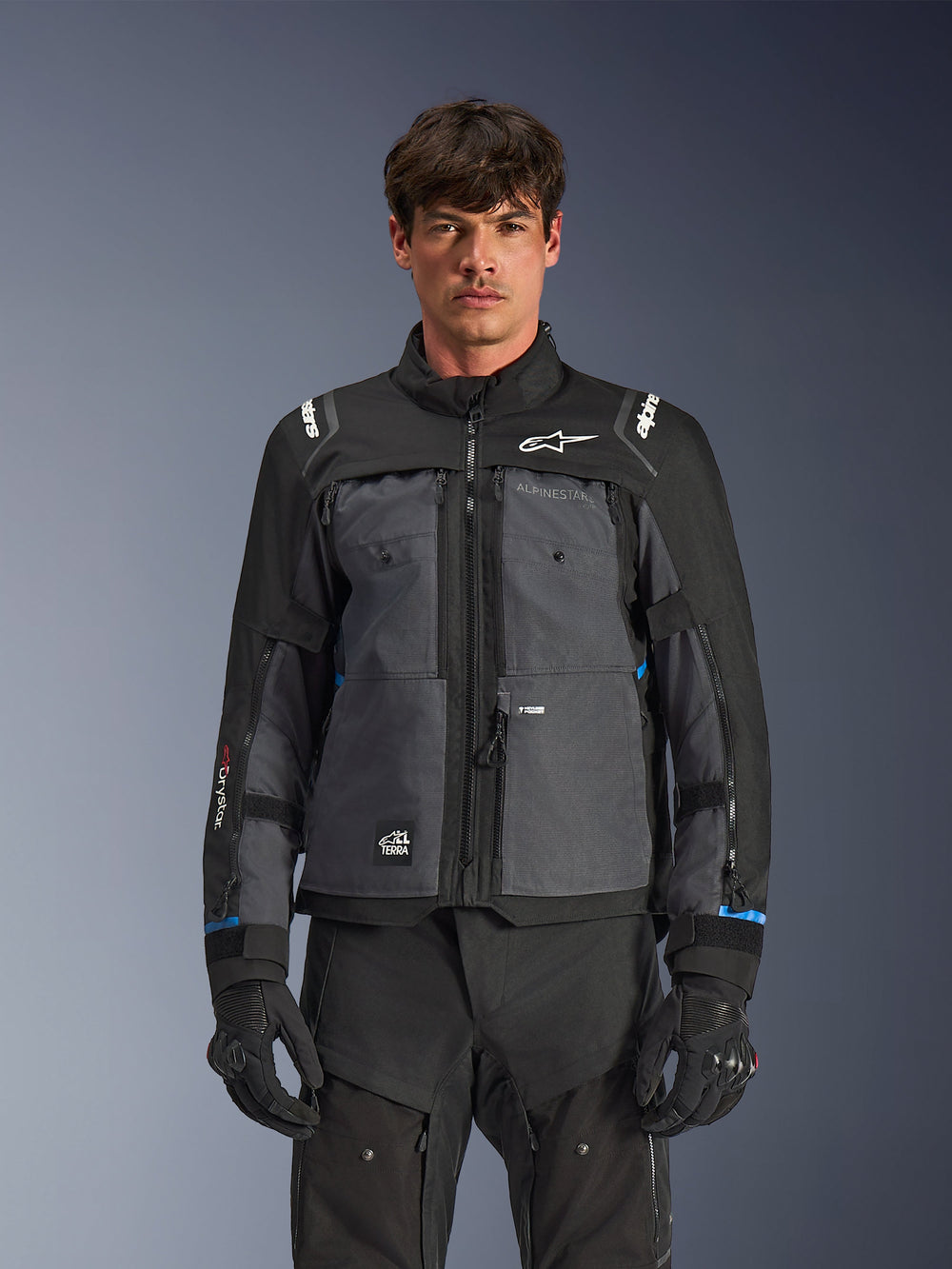 Alpinestars Cusco Drystar® Jacket, Motorcycle Touring Jacket, Black and Deep Gray, front view on model, featuring Alpinestars logos on chest and shoulders, Drystar® sleeve branding, technical multi-pocket design with ventilation zippers, paired with black riding gear