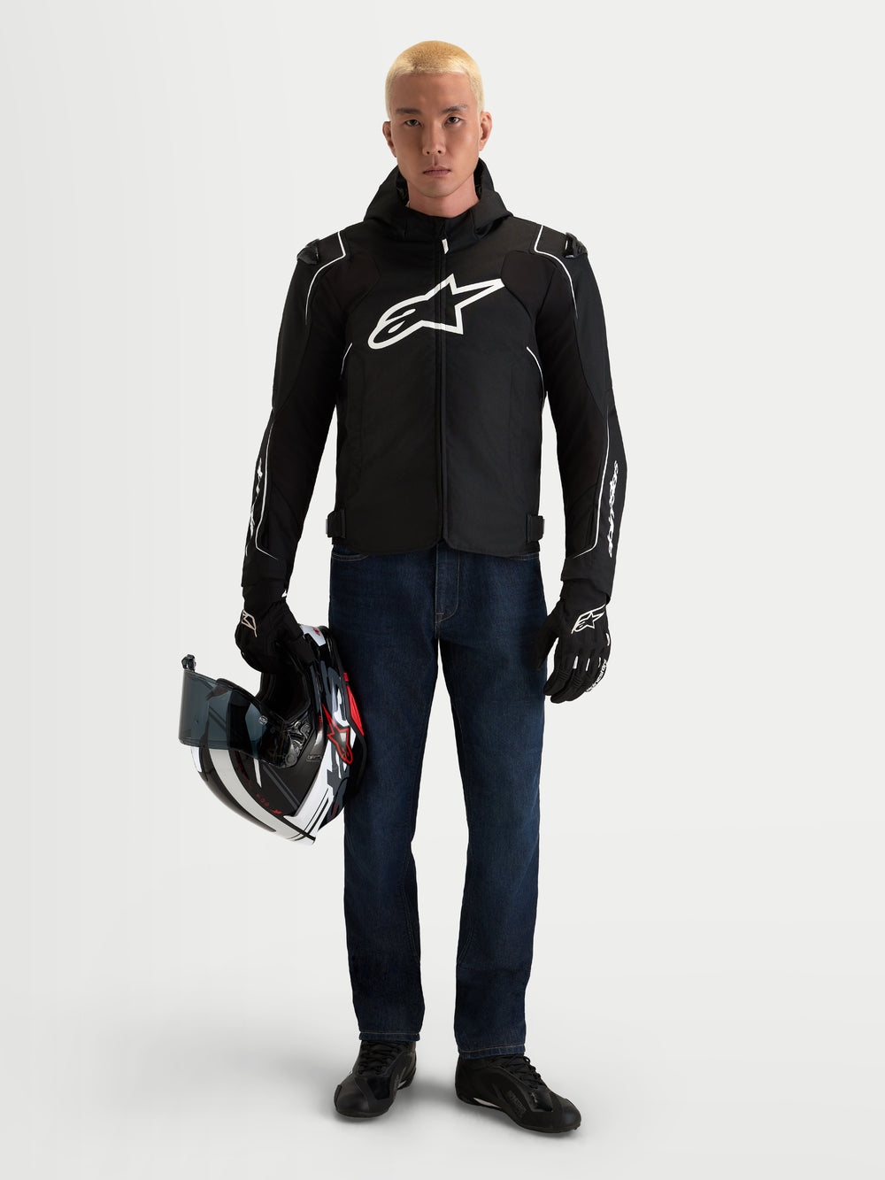 Alpinestars Zaca V2 Waterproof Jacket, Men's Black and White textile motorcycle riding jacket with integrated hood, worn by a model holding a helmet
