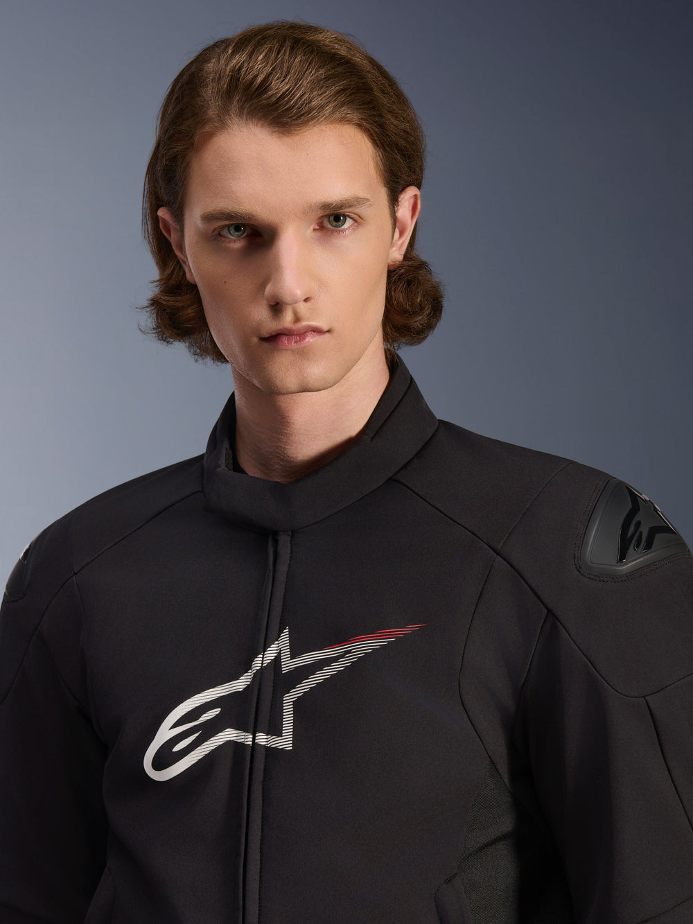 Model wearing Alpinestars SMX Waterproof Jacket, Black with White and Bright Red accents, featuring a large white star logo with a red streak on the chest, DFS Lite shoulder protectors, and a sleek textile construction for road motorcycle performance.