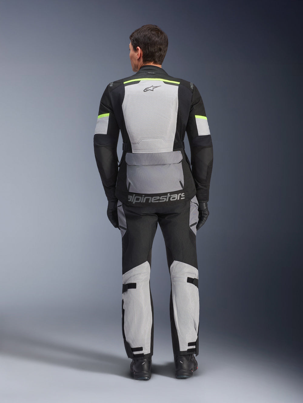 Alpinestars Andes Air Drystar® Jacket and Pants, Ice Gray Dark Gray Black adventure touring kit, rear view of rider wearing complete gear with neon yellow accents, featuring large mesh ventilation panels and Alpinestars branding.