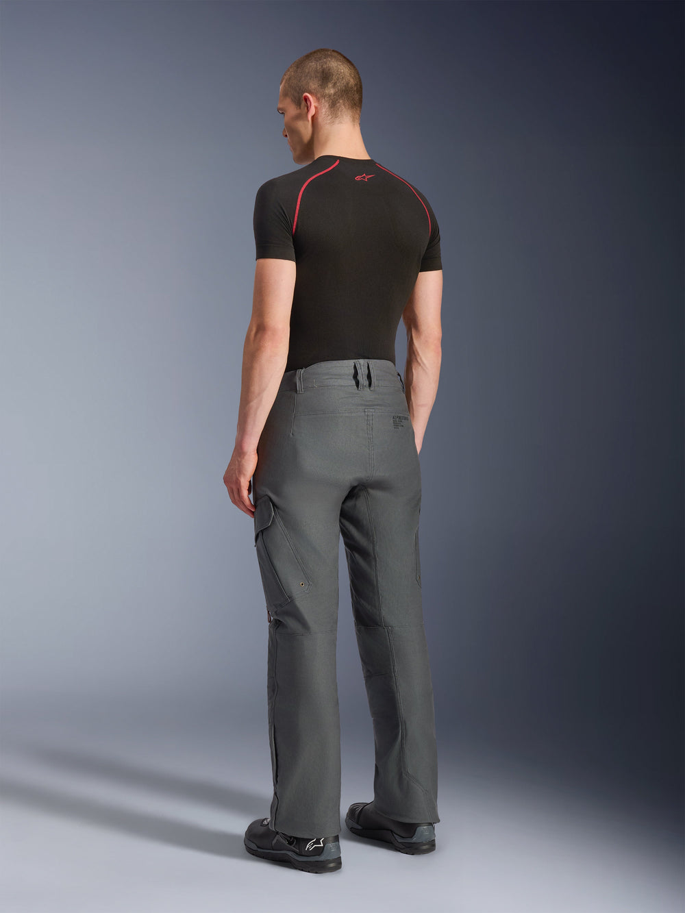 Alpinestars Borrego Drystar® Pants, Adventure Motorcycle Pants, Anthracite Gray, rear view, featuring a waxed-canvas look with cargo pockets, paired with a black t-shirt and riding boots, durable design for road and adventure touring