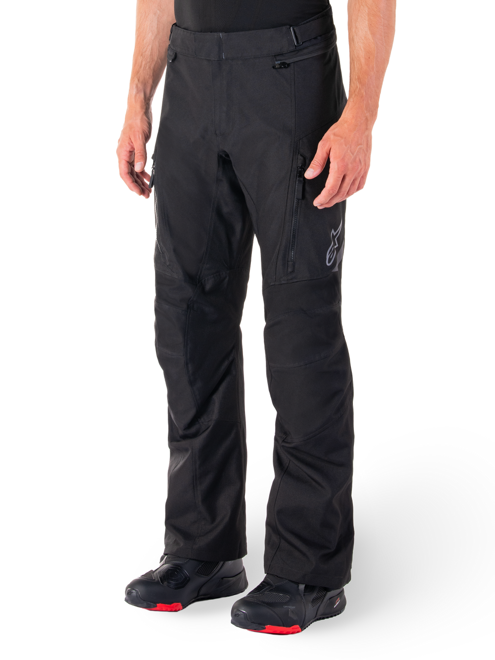 Alpinestars ST-1 Waterproof Pants, Black Motorcycle Touring Pants, worn with black and red riding boots, featuring zippered front pockets and a subtle star logo on the thigh, ergonomic design for adventure and road riding.