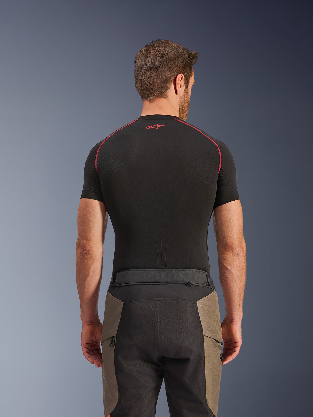 Alpinestars Cusco Drystar® Pants, Adventure Riding Pants, Walnut Black, rear view showing waist details and color-blocked design, worn with a black short-sleeve base layer with red stitching and logo
