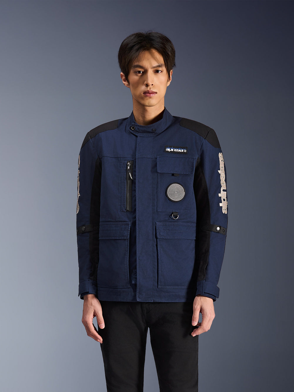 Alpinestars Dice Jacket, Urban Motorcycle Jacket, Dark Blue and Black, featuring a multi-pocket field jacket design with a spiral chest patch and white Alpinestars branding on the sleeves, modern workwear-inspired riding apparel
