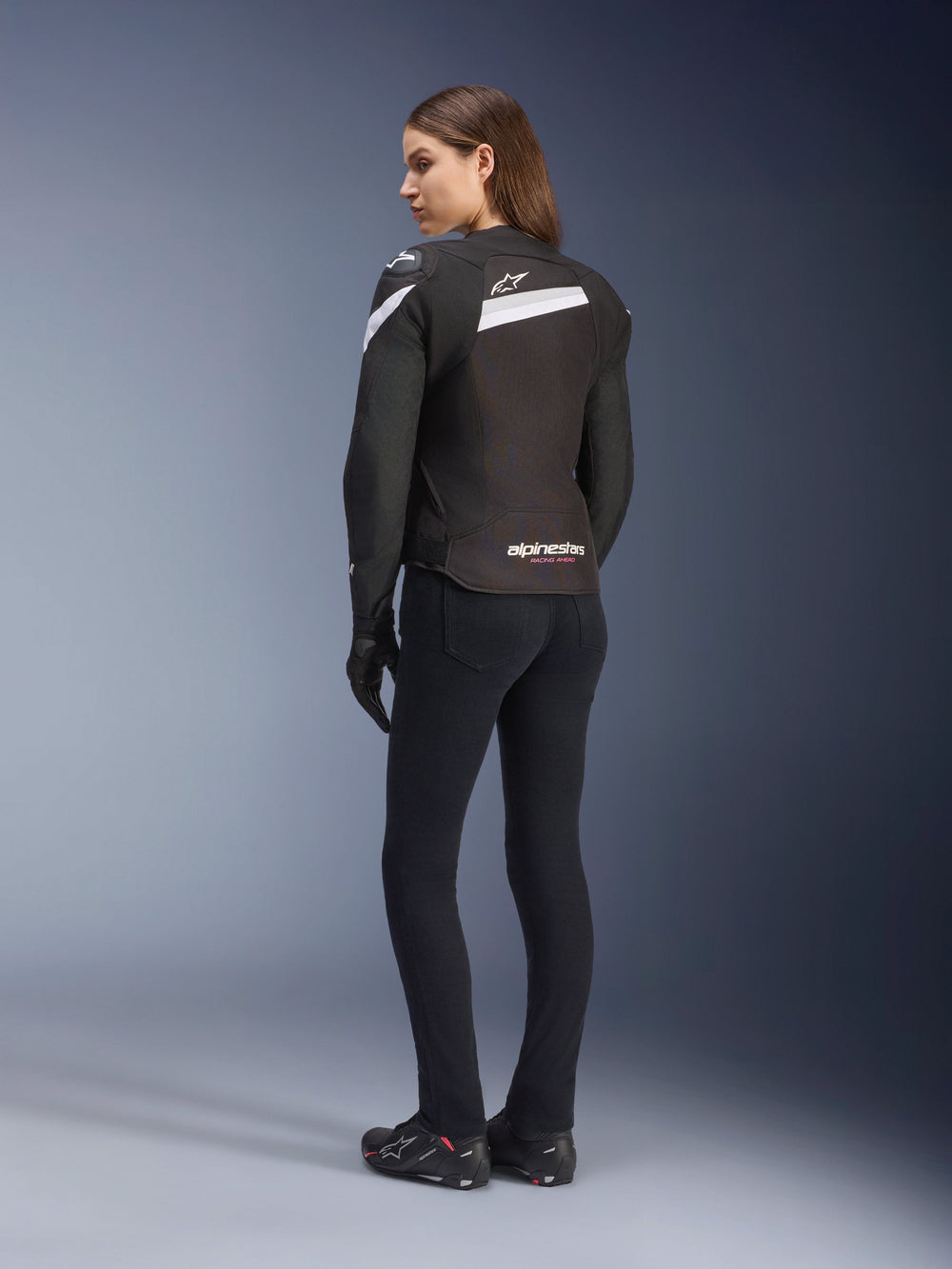 Alpinestars Stella T-GP Plus R V4 Jacket, Women's Textile Motorcycle Jacket, Black and White, back view on model, featuring white shoulder accents and Alpinestars logo, worn with black pants and riding gloves, sport-fit design for road riding