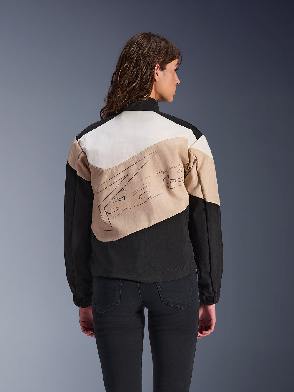 Alpinestars Stella Moshell Jacket, Women's urban motorcycle jacket, Black Sand and Off-White, back view on a model, asymmetrical color-blocked design with large back graphic, modern streetwear-inspired protective riding gear