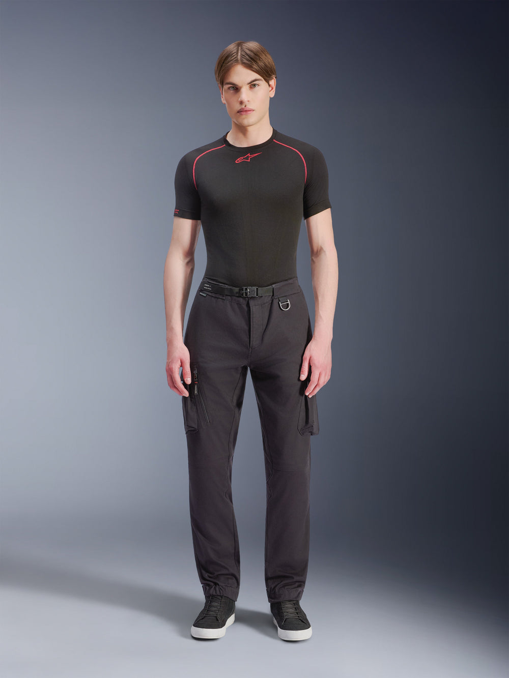 Alpinestars Flex-AST Cargo Pants, Black, urban motorcycle pants worn by a male model with a black short-sleeved top and sneakers, featuring a regular tapered fit, cargo pockets, and integrated belt buckle detail