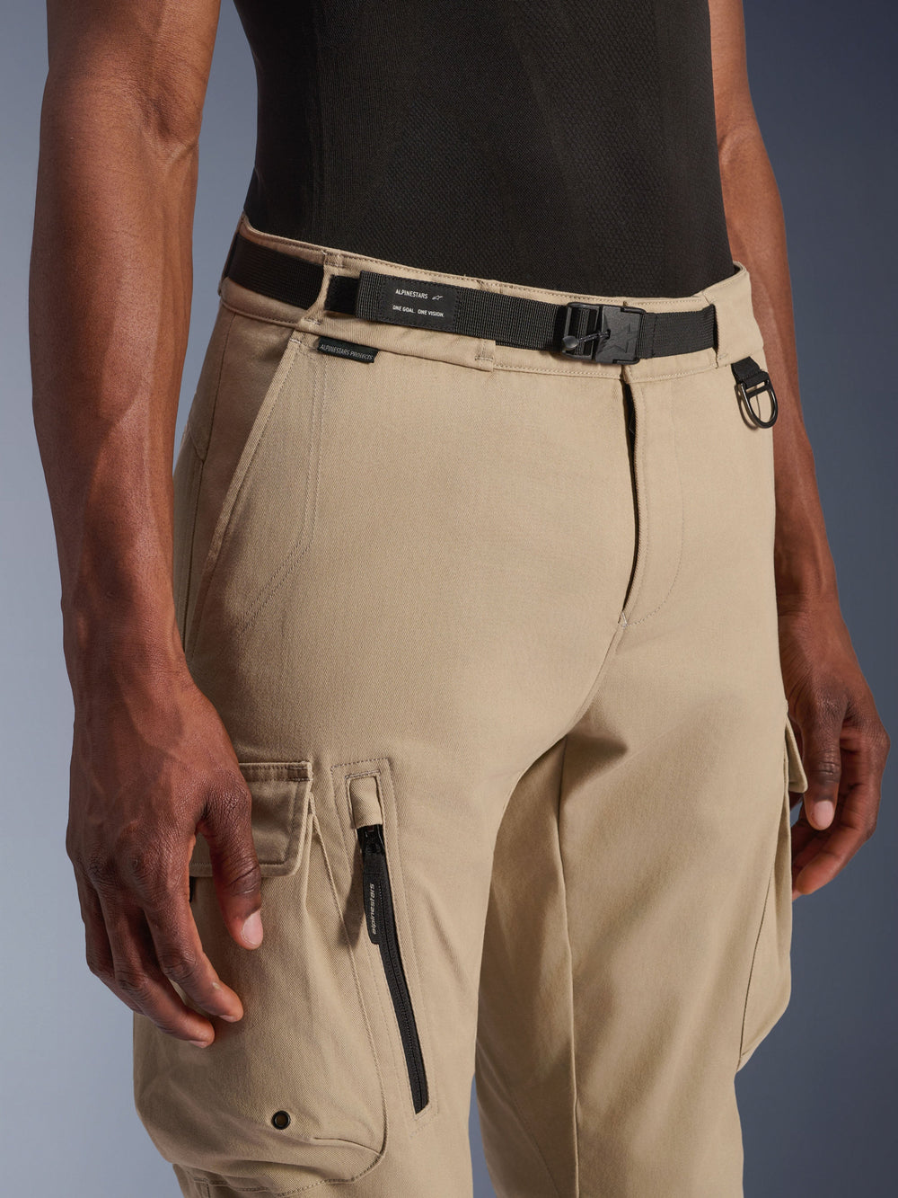 Alpinestars Flex-AST Cargo Pants, Motorcycle Cargo Pants, Light Beige, featuring an integrated black webbing belt with branding, metal D-ring, side zipper pocket, and durable twill fabric for a utilitarian urban riding look