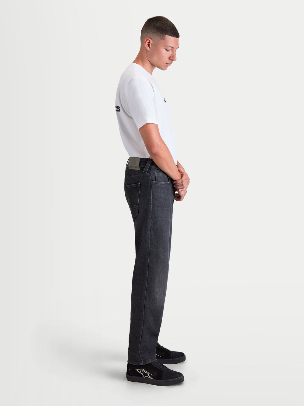 Alpinestars Flex-AST 8 Denim Pants Short, men's urban motorcycle riding jeans in Used Black, side profile view on a model wearing a white t-shirt, featuring AA-rated single-layer technical denim and comfortable regular straight-leg fit.